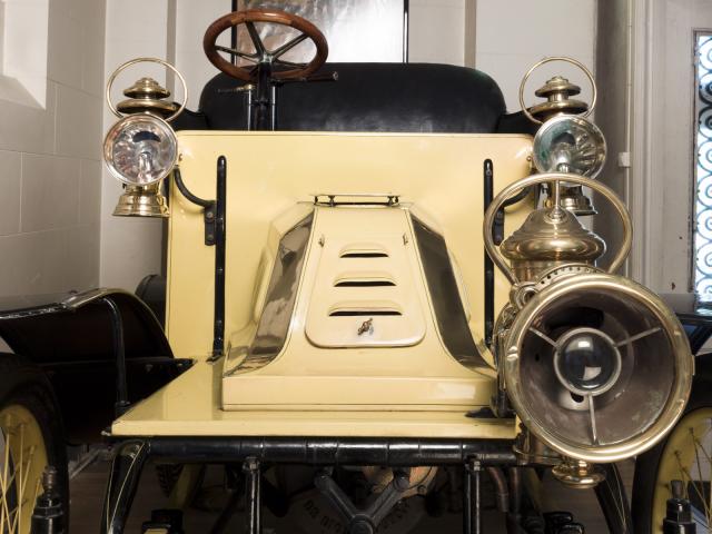 Automobile De Dion Bouton type Q surnommée la populaire de couleur jaune deux types de phares deux à pétrole et un à gaz acétylène placé plus avancé sur la partie gauche à l'avant de l'automobile