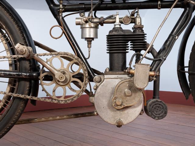 Motocyclette WERNER noire 1904-1905 moteur 4 temps bicylindre en ligne transversal 352 cm3 (55 x 74 mm) soupapes d'admission automatiques allumage électrique commandé par rupteurs piles et bobines placées dans un compartiment du réservoir transmission directe par courroie trapézoïdale