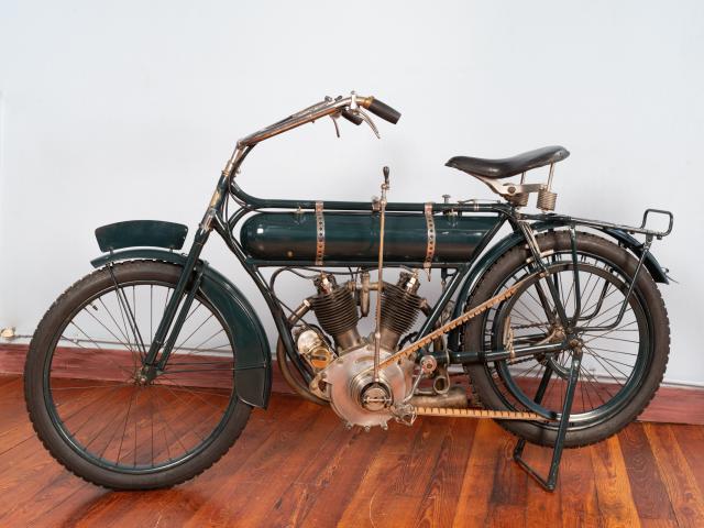 Motocyclette MAGNAT DEBON 4 HP 1914 moteur bicylindre en V 4 temps 500cm3 cylindres borgnes soupapes en tête allumage par magnéto transmission par variateur et courroie suspension avant par fourche télescopique pas de suspension arrière frein arrière double vitesse 90km/h
